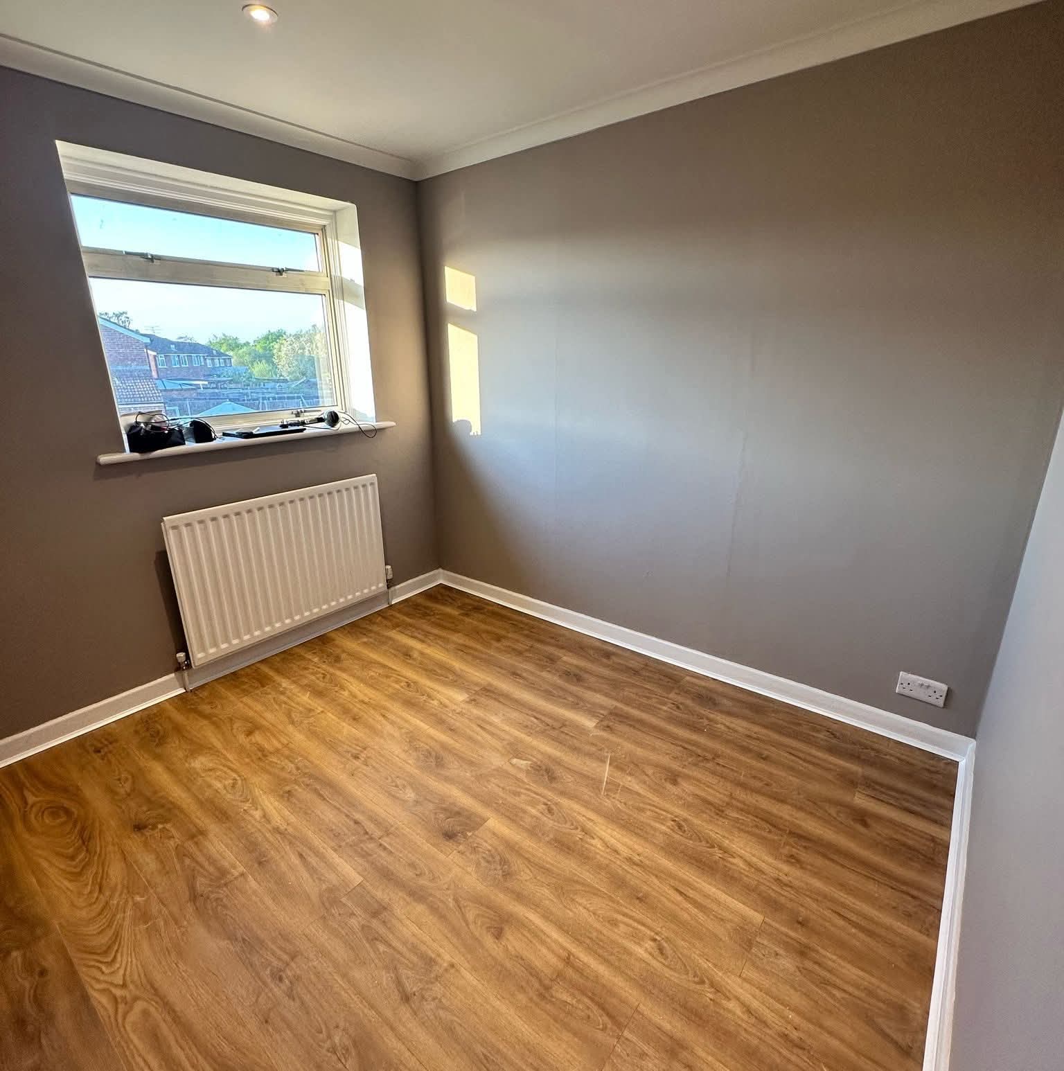 Haya UK gallery photograph of smooth-looking painted grey walls, white skirting and wood-effect flooring.